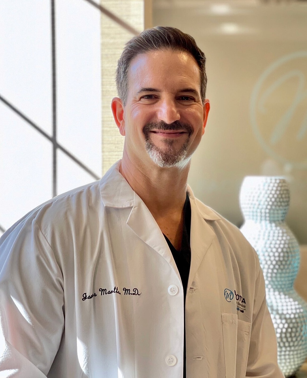 Smiling doctor wearing a lab coat indoors.