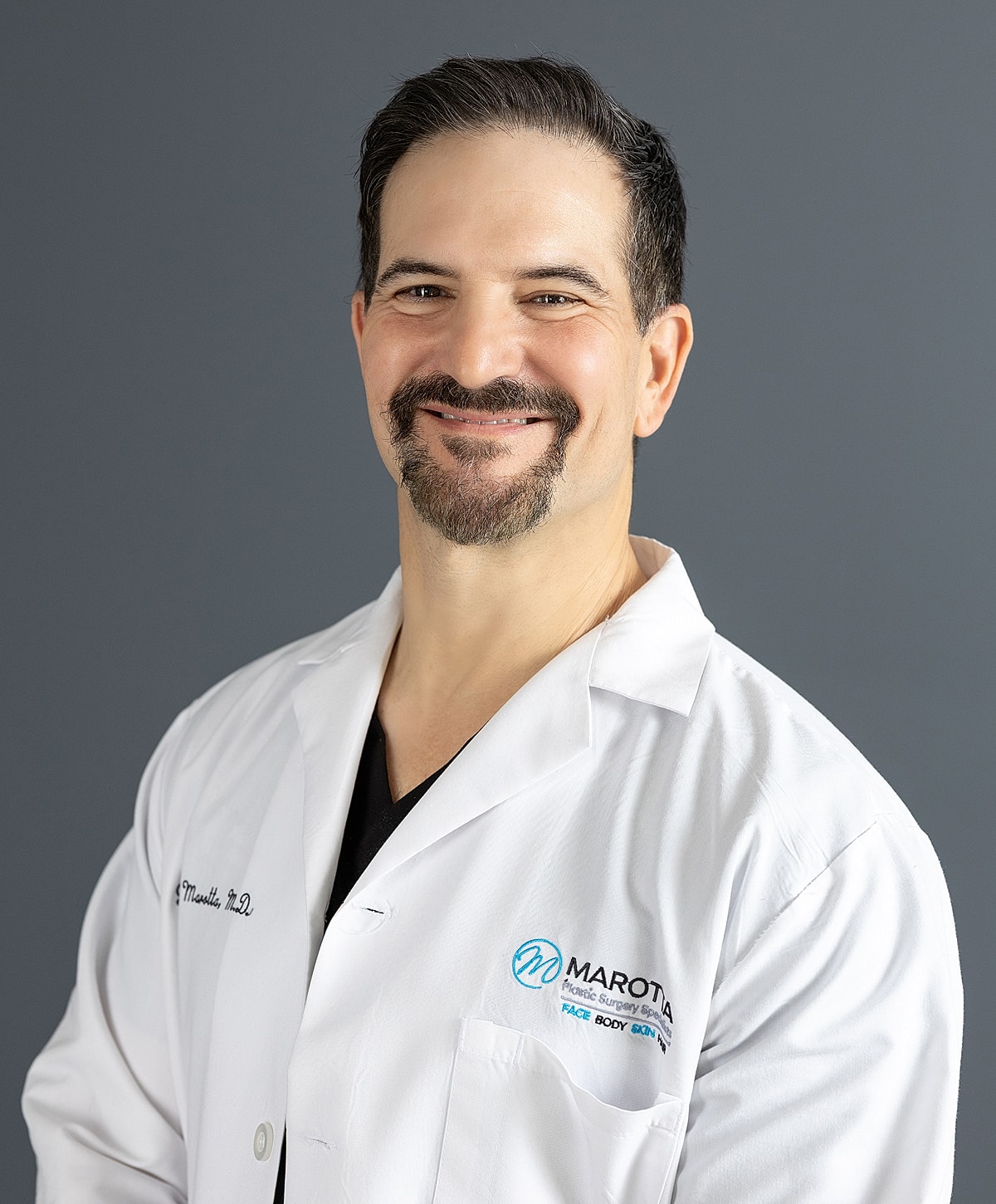 Male physician smiling in a white coat.