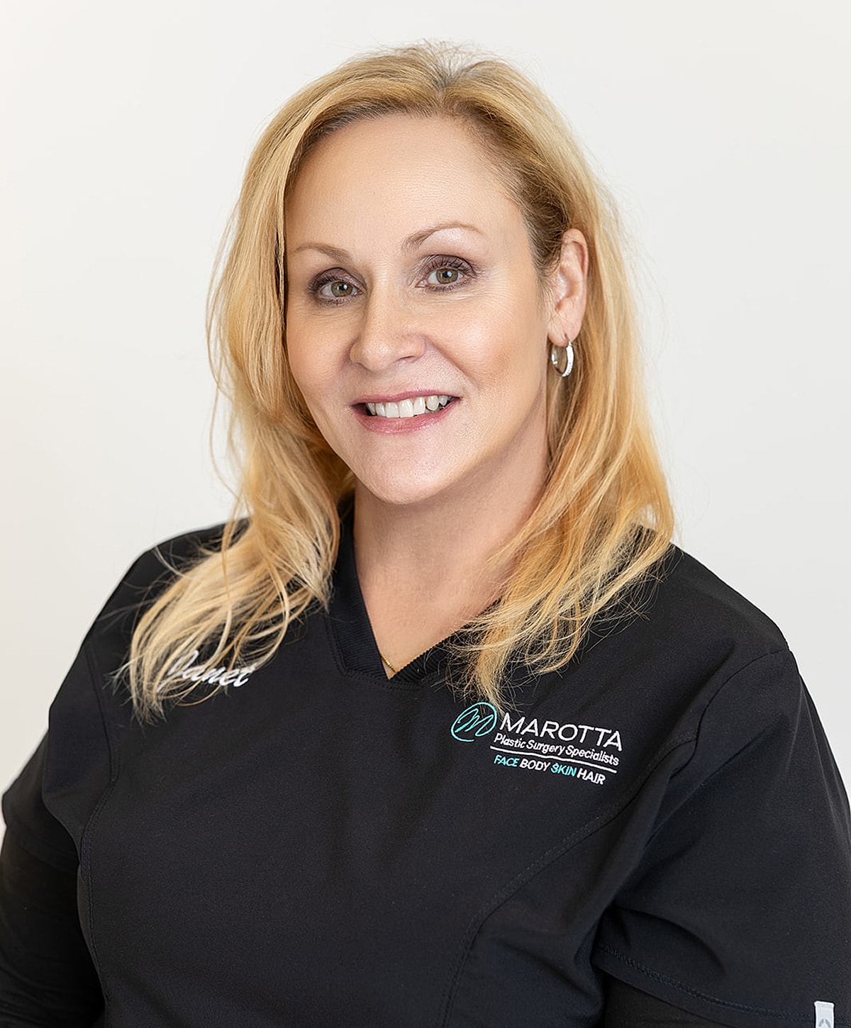 Smiling professional in medical attire against white background.