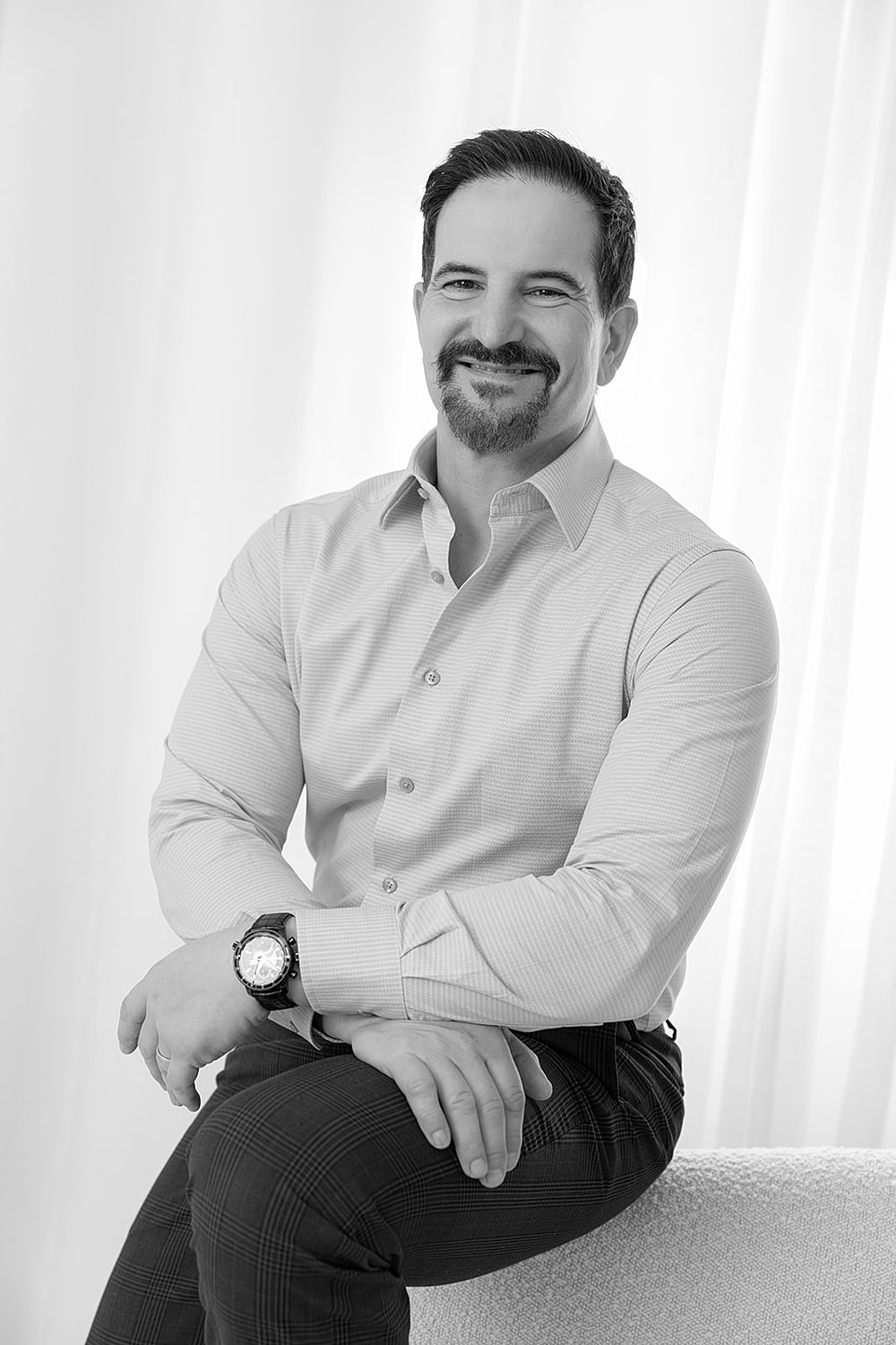 Smiling man sitting in a formal shirt.