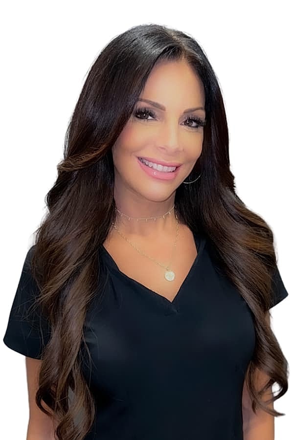Smiling woman with long brown hair and necklace.