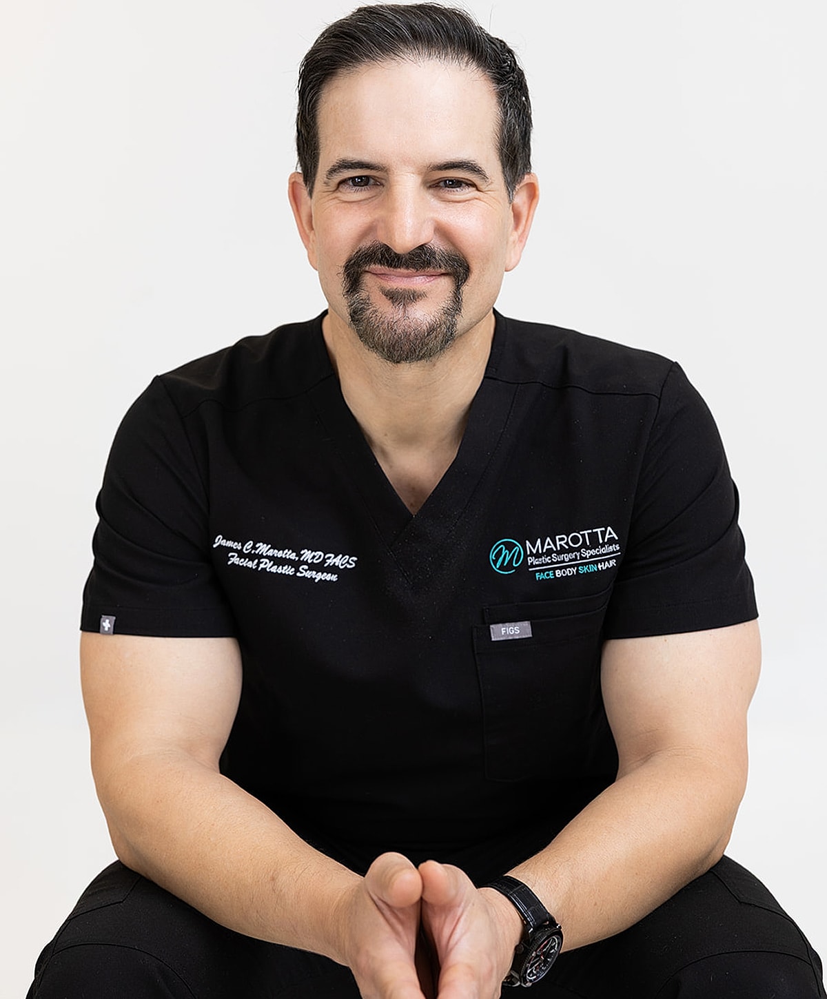Smiling male plastic surgeon in black scrubs.