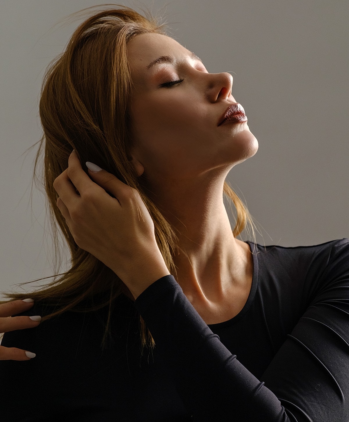 Woman styling her hair in soft lighting.