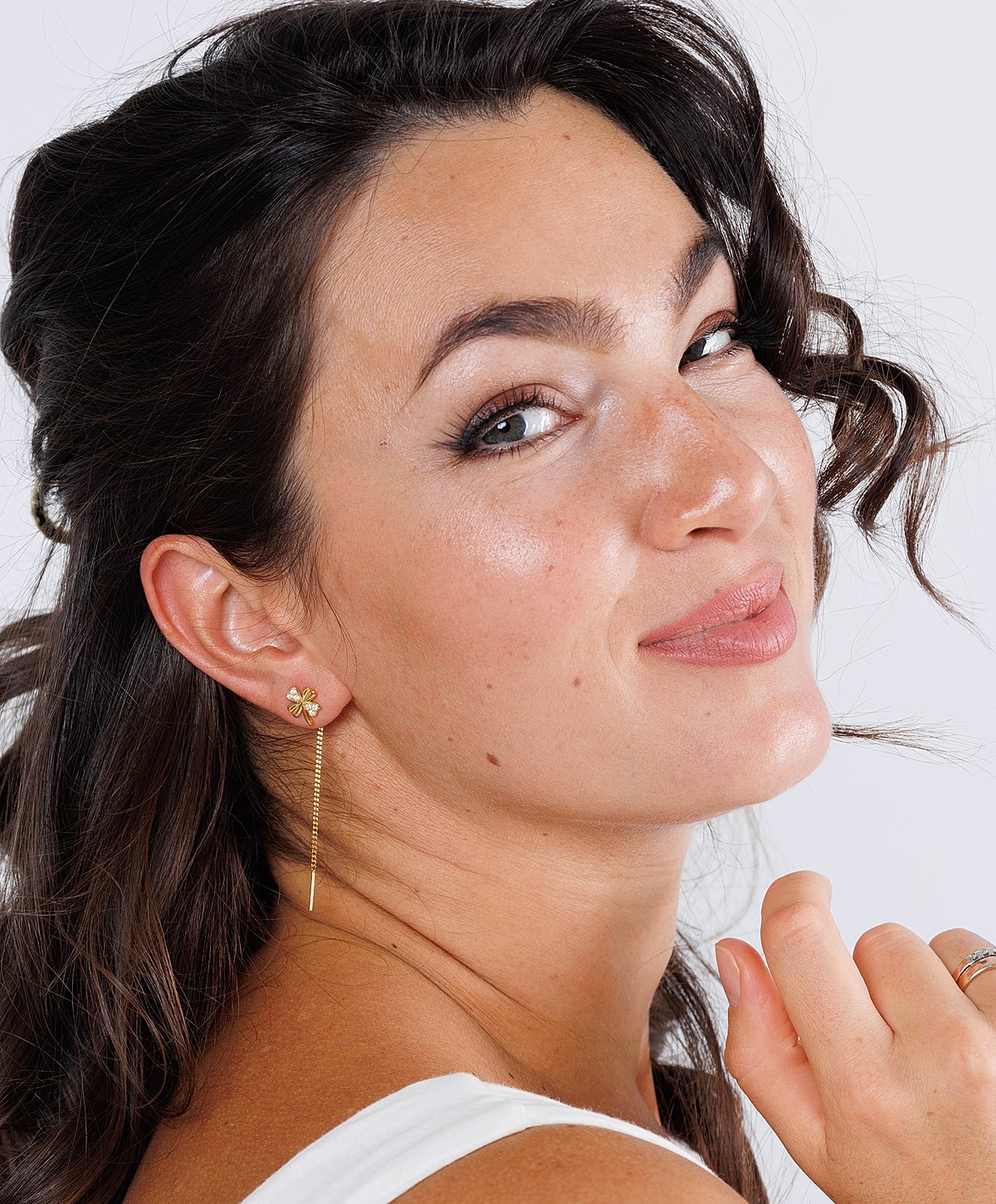 Woman smiling with elegant earrings and wavy hair.
