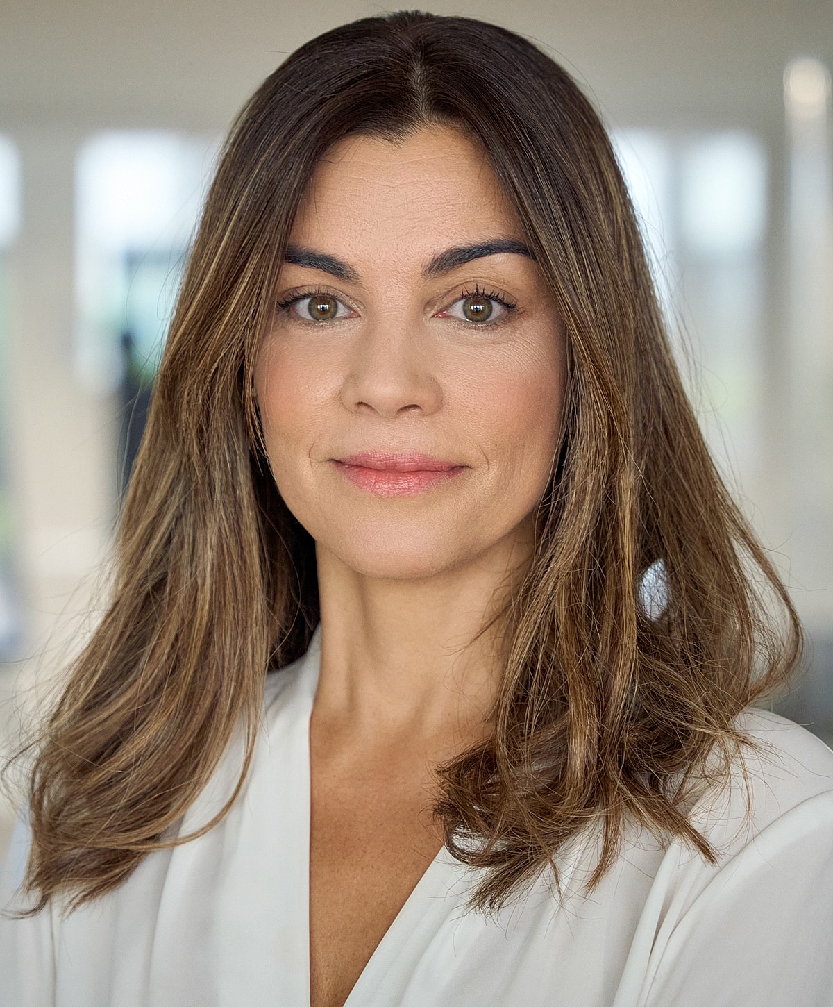 Woman with long hair, neutral expression, indoor setting.
