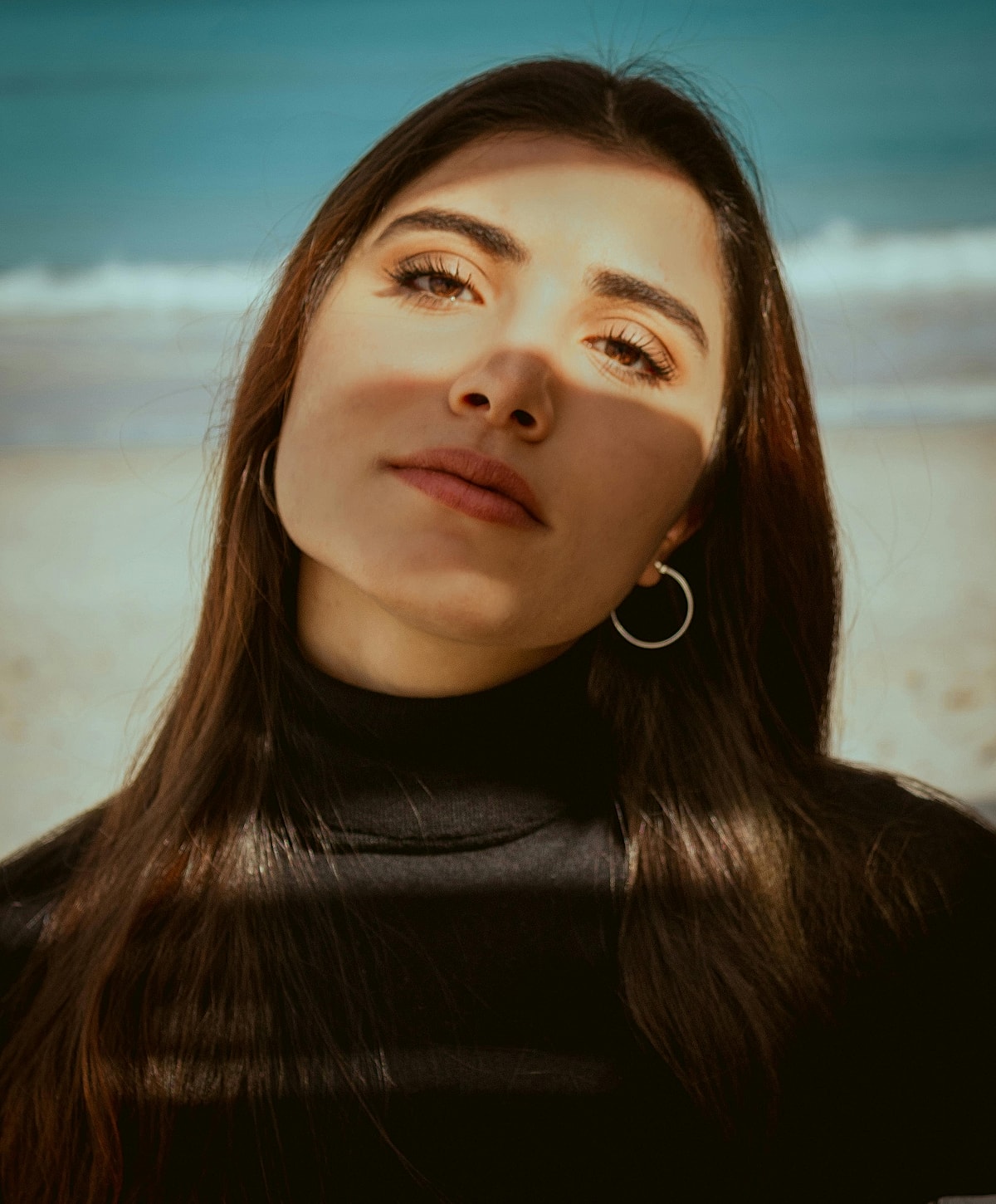 Woman in black top with beach background.