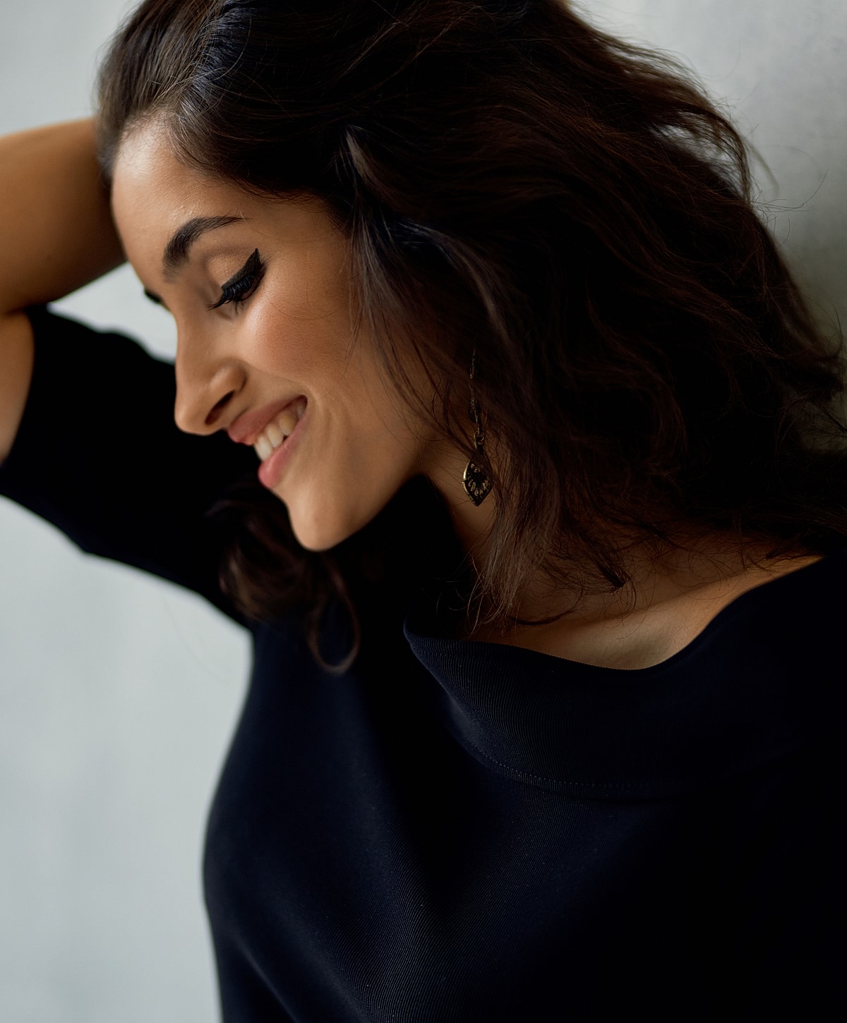 Woman smiling with curly hair and earrings