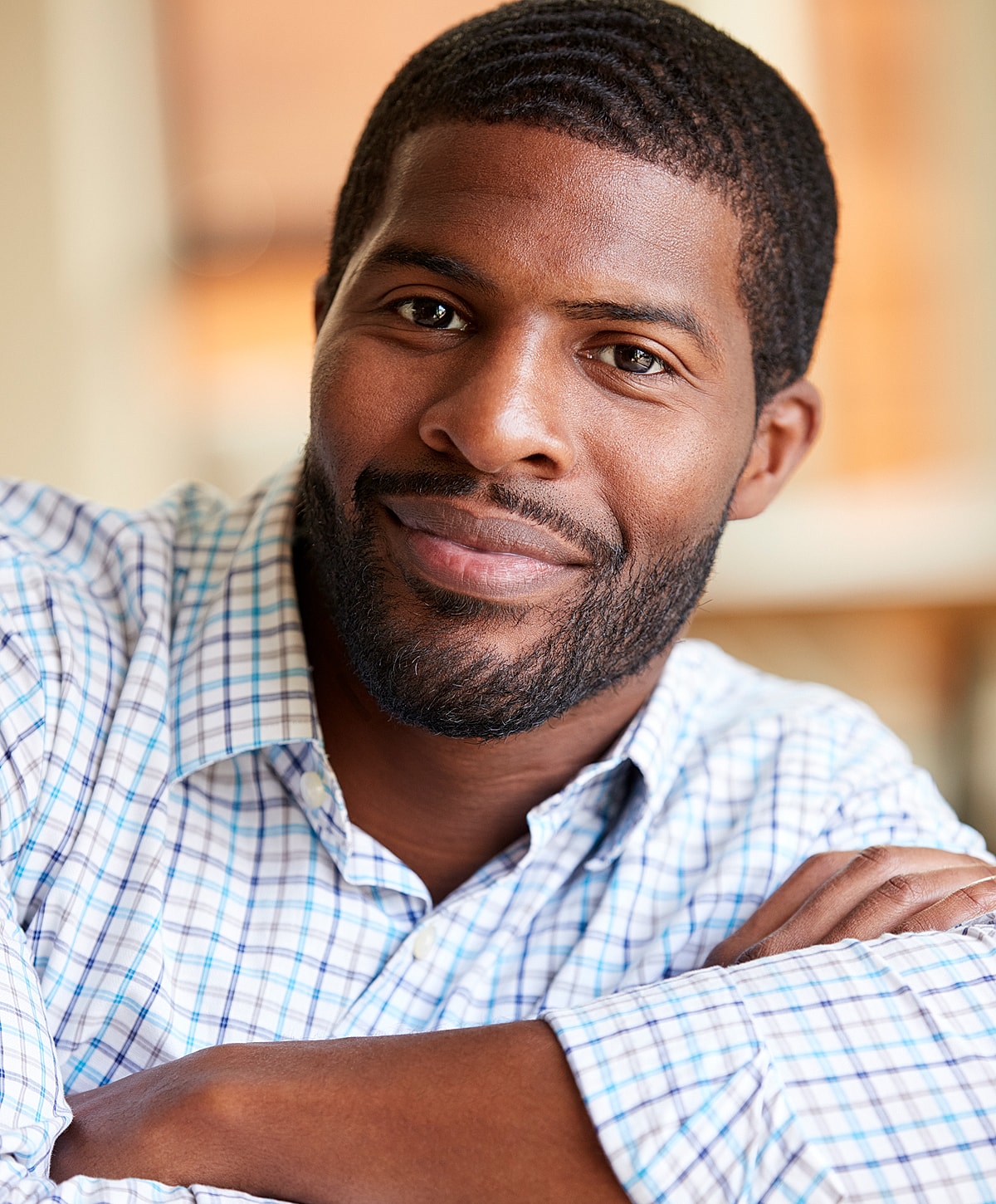 Smiling man with arms crossed, plaid shirt.