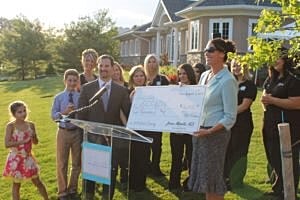 Group celebration with a large check presentation.