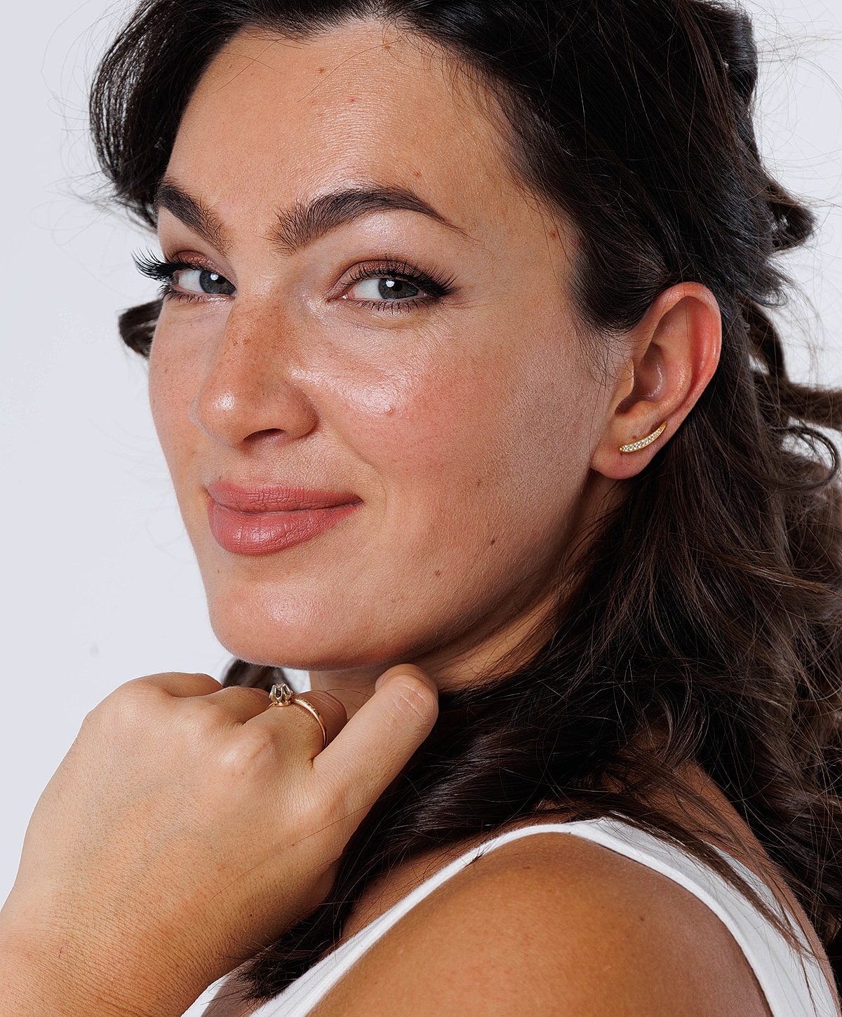 Woman smiling with elegant jewelry and hairstyle.