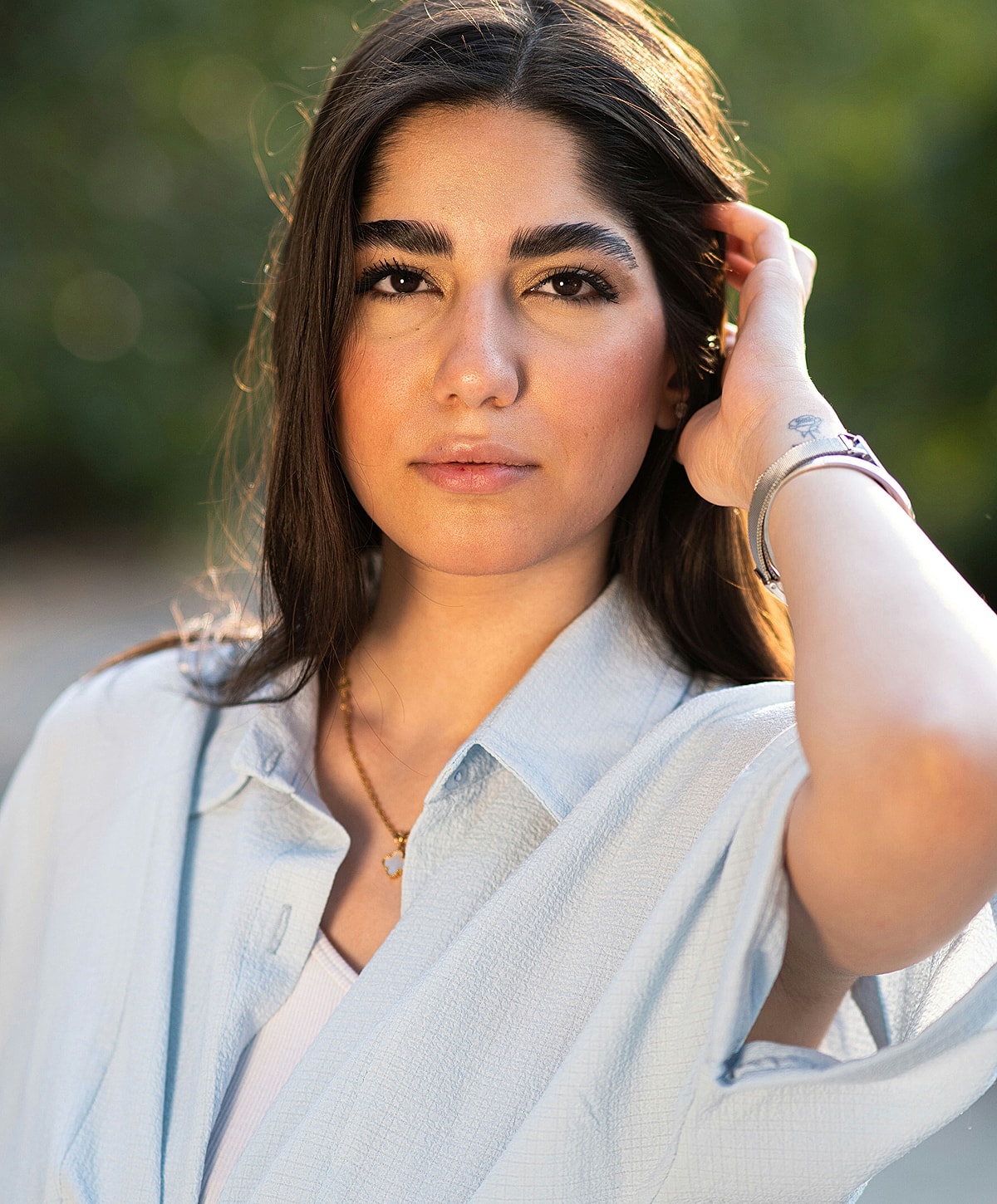 Young woman with long hair, outdoors, thoughtful expression.