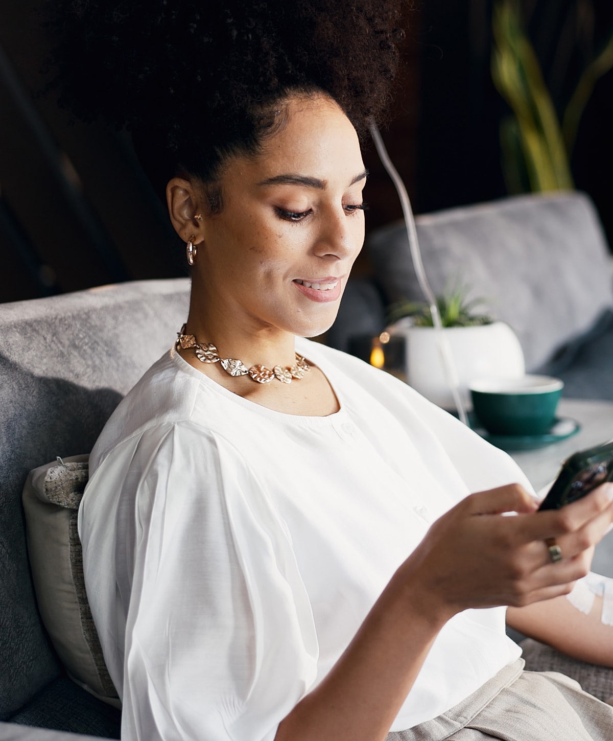 Woman in white blouse using smartphone, smiling.