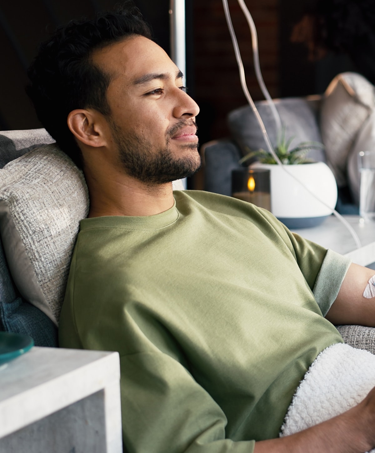 Man relaxing on a sofa, wearing green shirt.