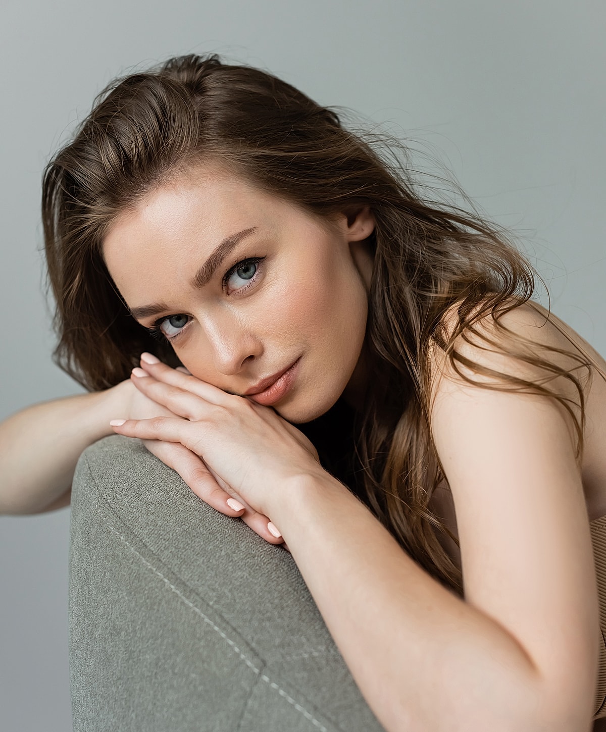 Young woman with long hair resting on cushion.