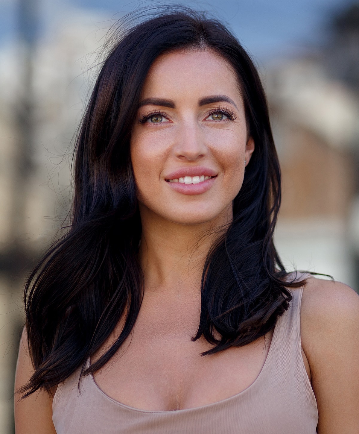 Smiling woman with long dark hair outdoors.
