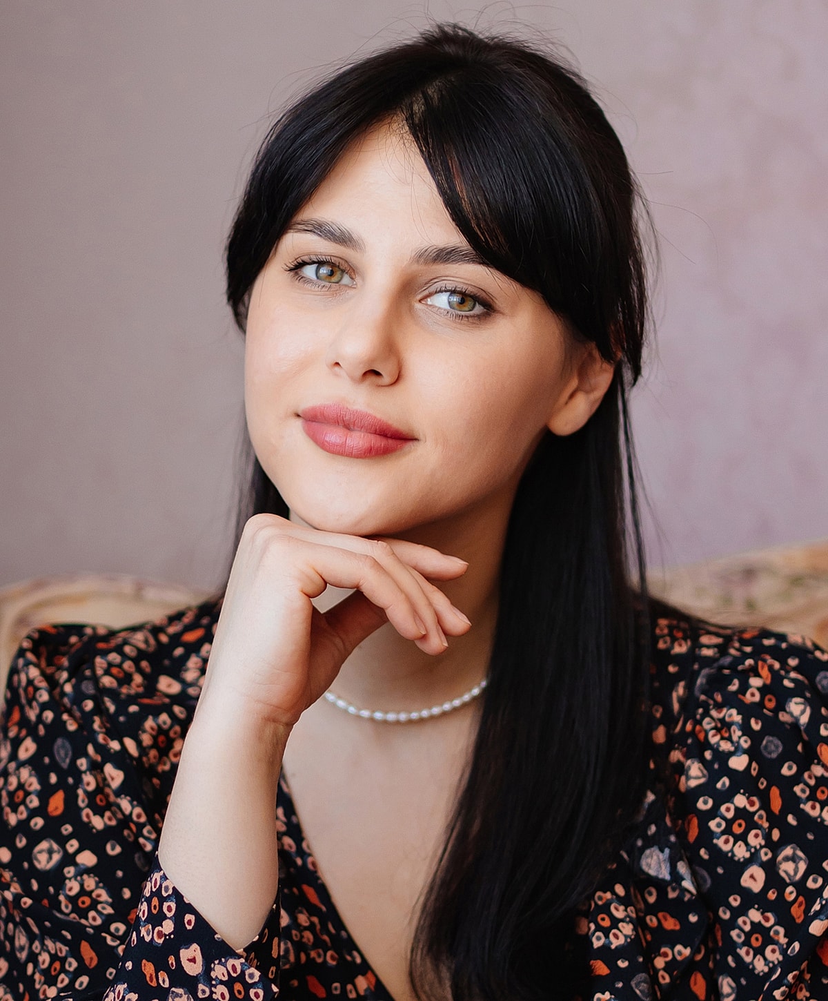 Young woman with long black hair and thoughtful expression.