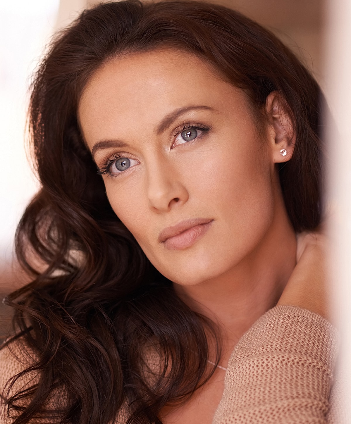 Woman with wavy hair in soft lighting.