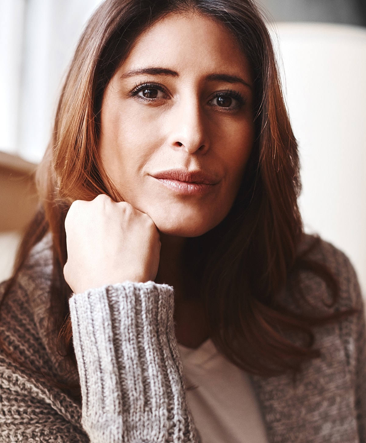 Thoughtful woman resting chin on hand.