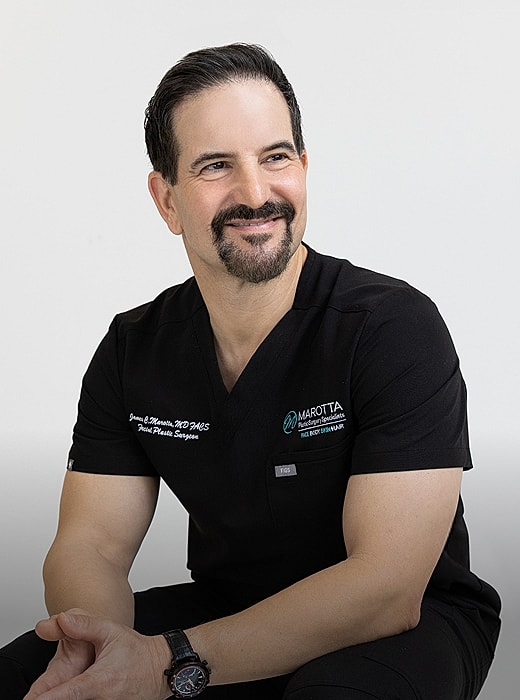 Smiling surgeon in black scrubs, professional portrait.