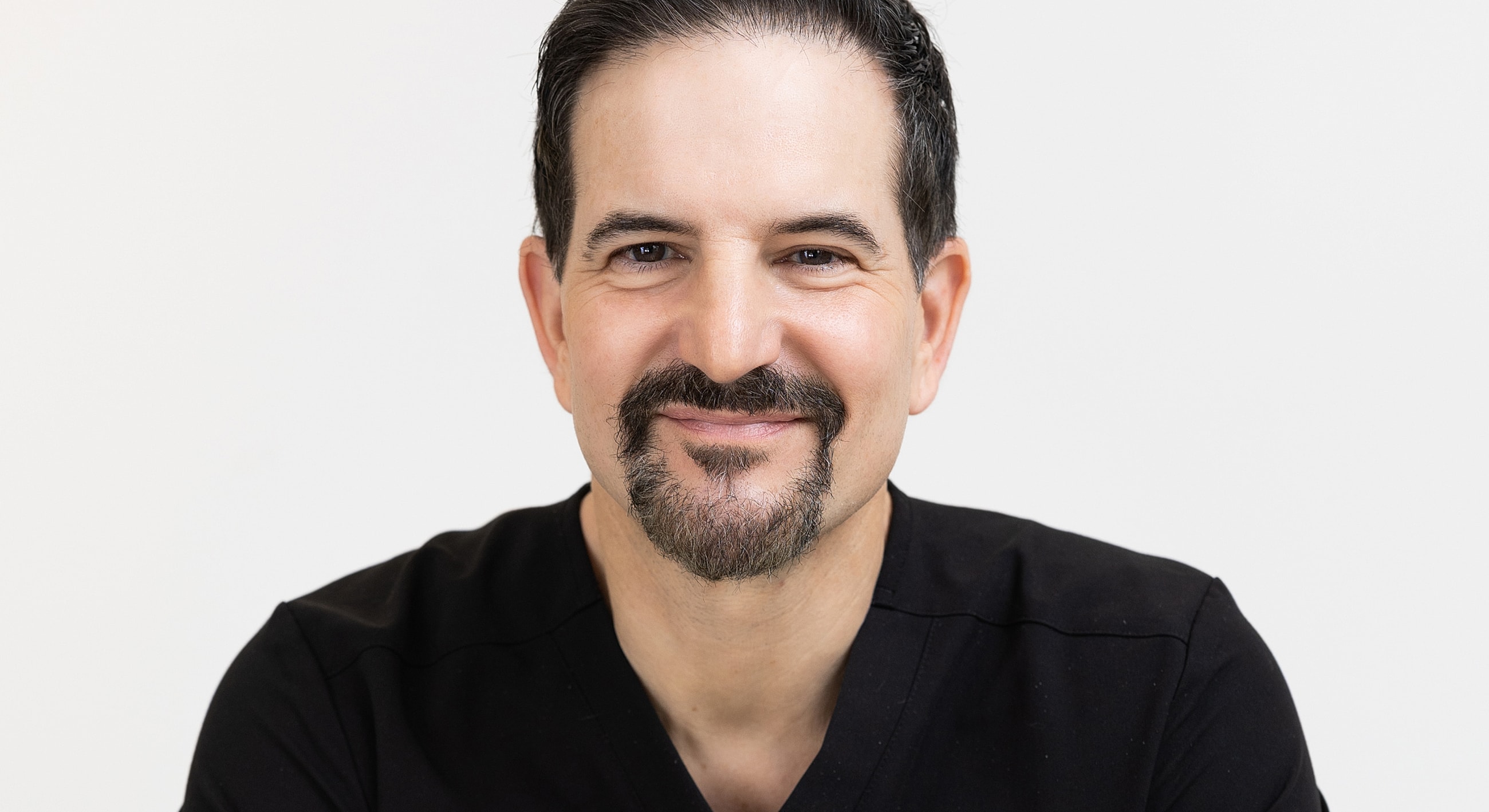Smiling man in black shirt against white background.