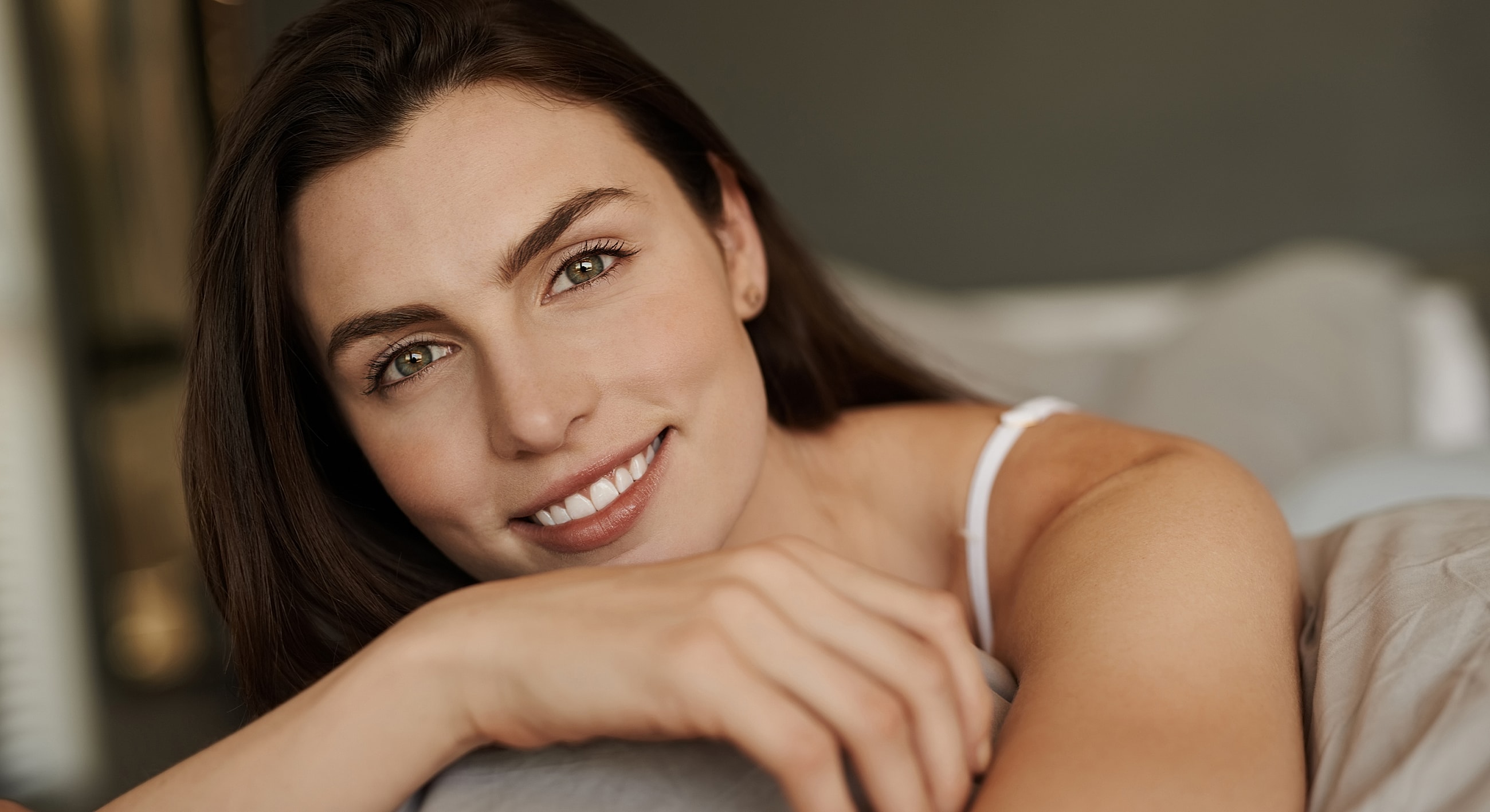 Smiling woman relaxing on soft bedding.