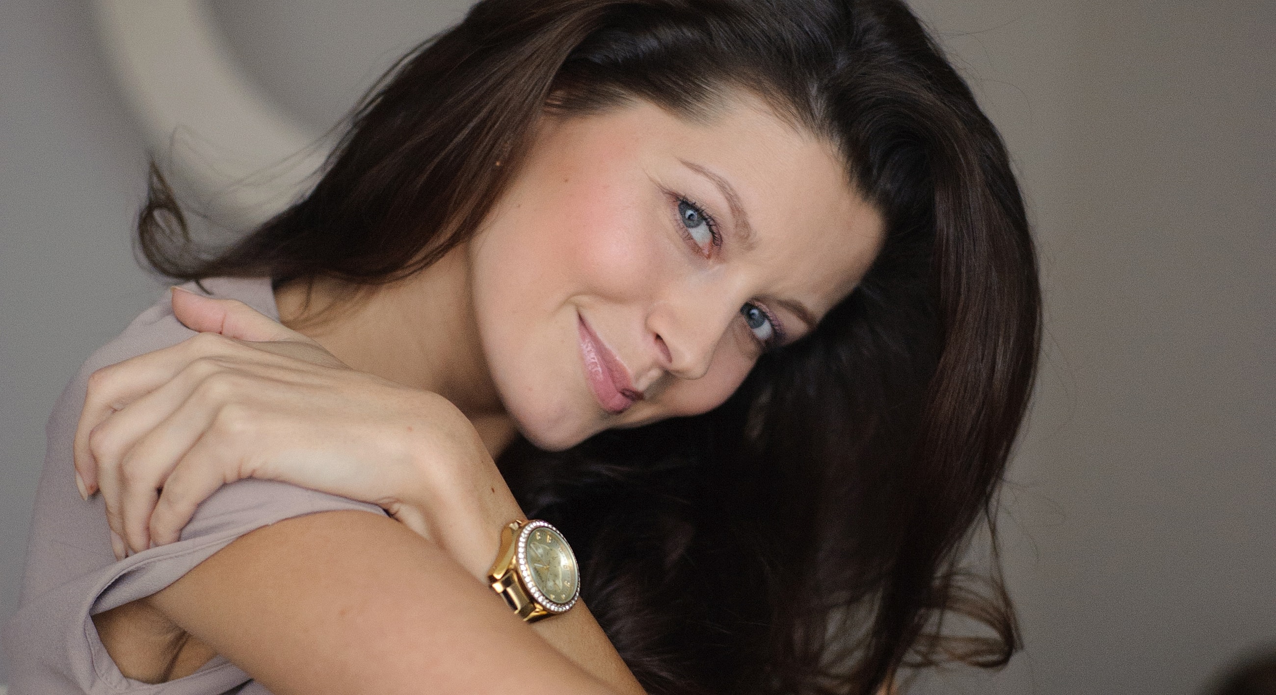 Smiling woman with long hair and elegant watch.