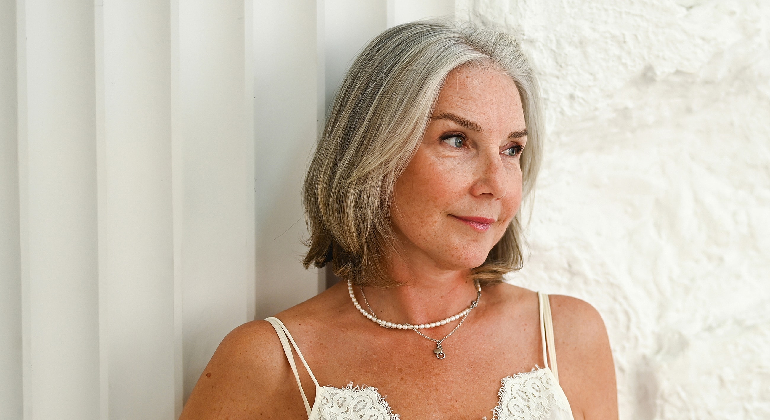 Woman with short gray hair and pearl necklace.