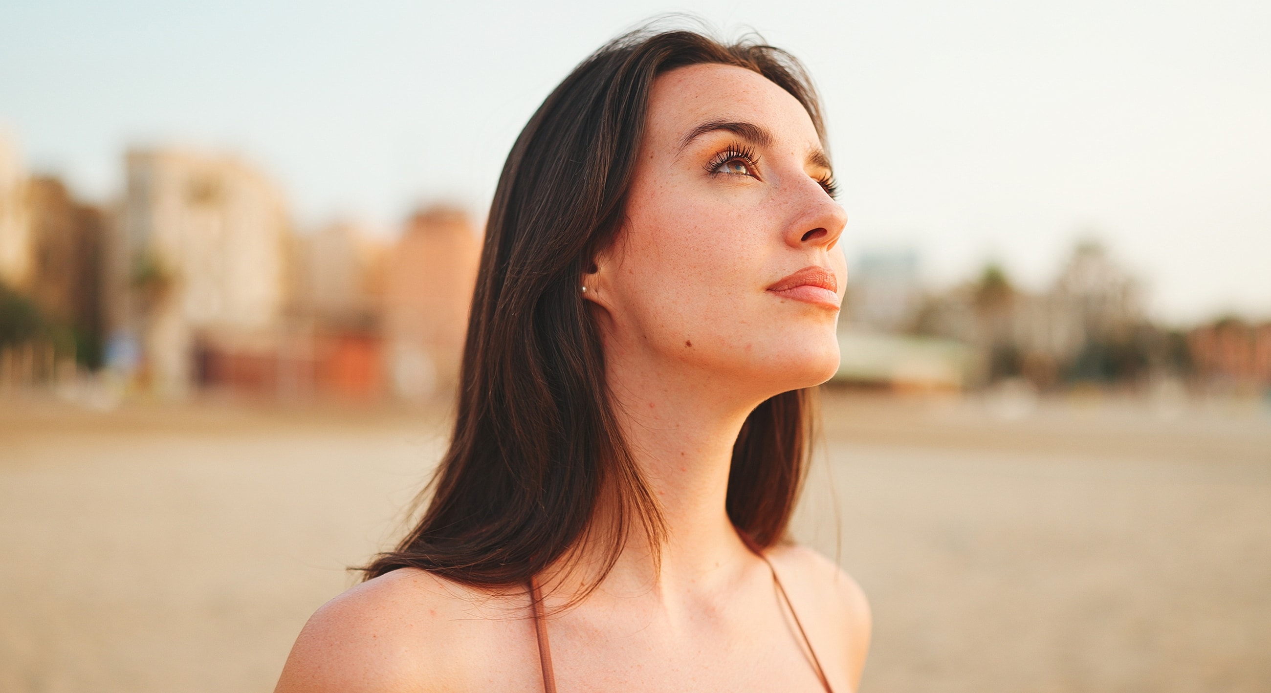Woman gazing upwards at sunset beach scene