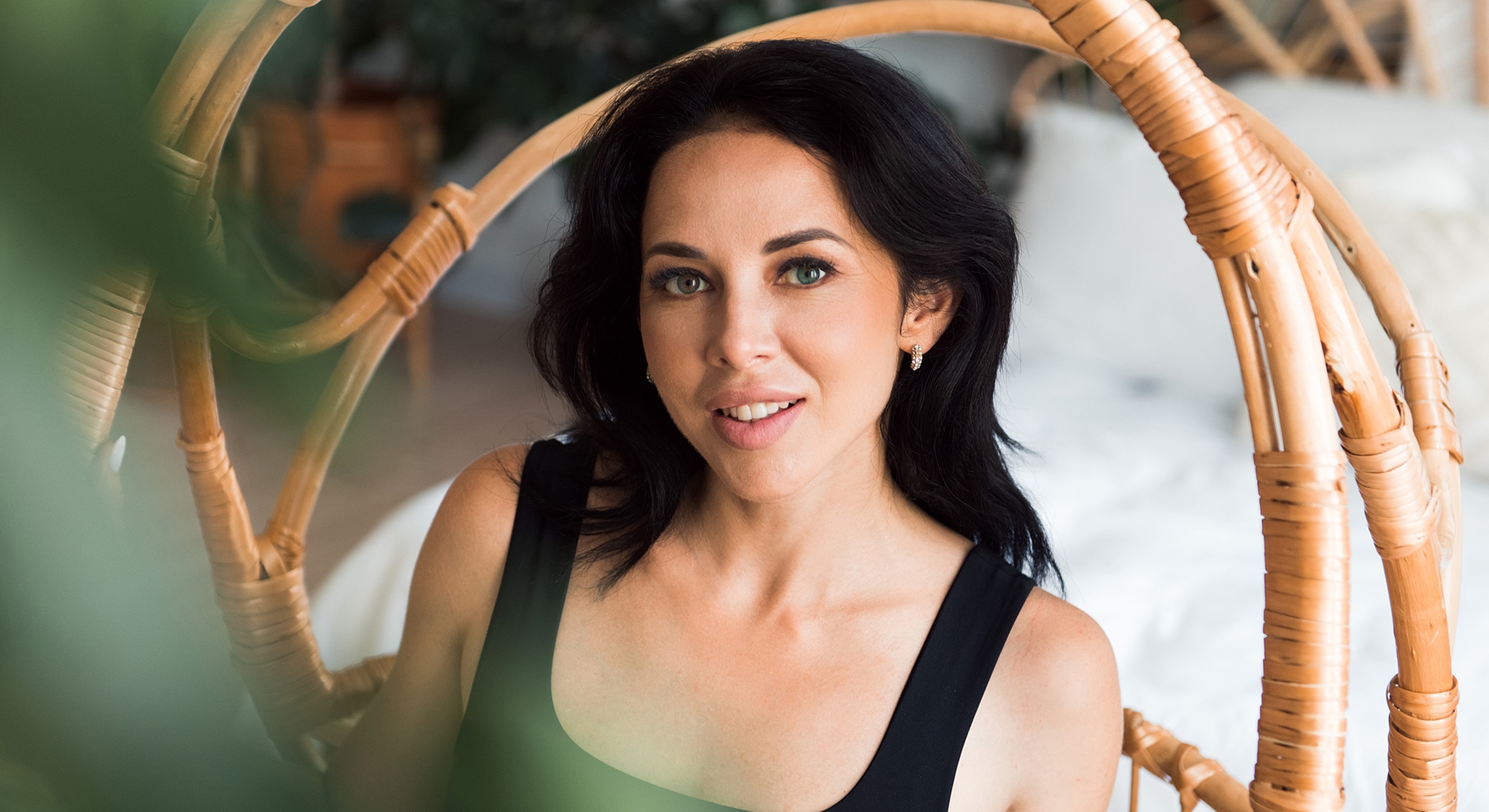 Woman sitting in a rattan chair, smiling.