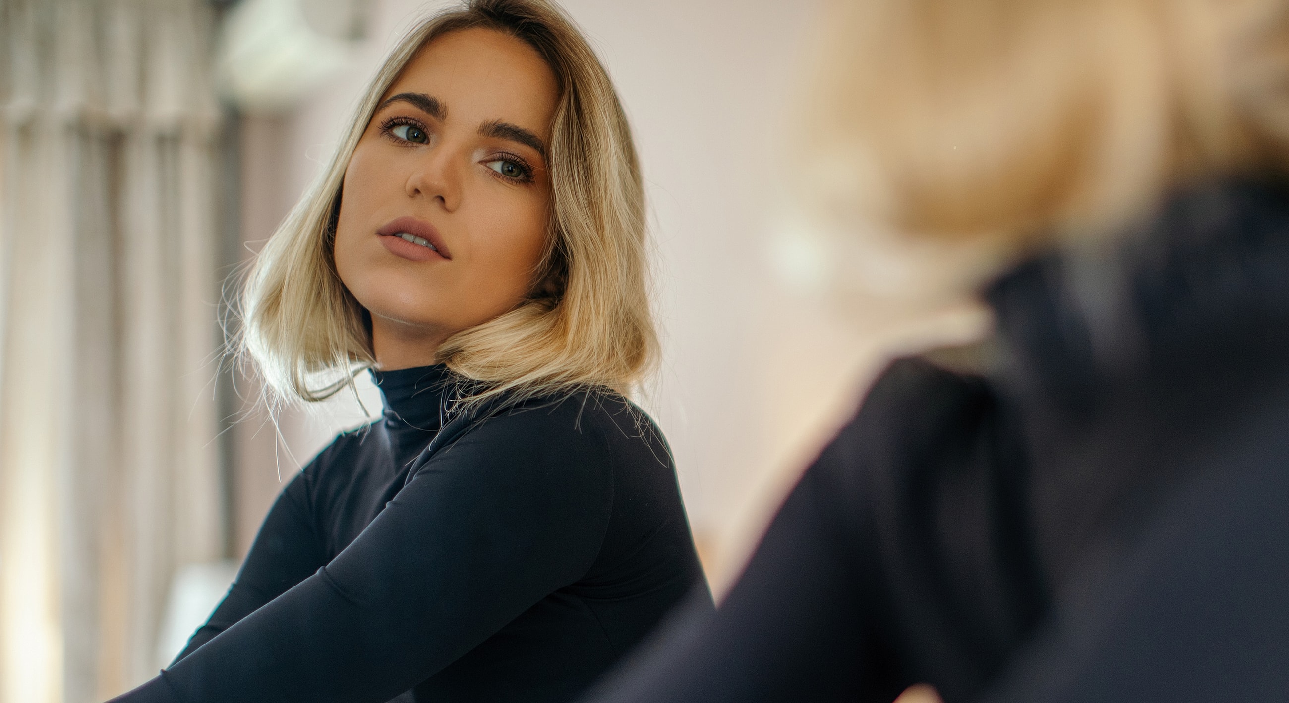 Woman with blonde hair looking in mirror.