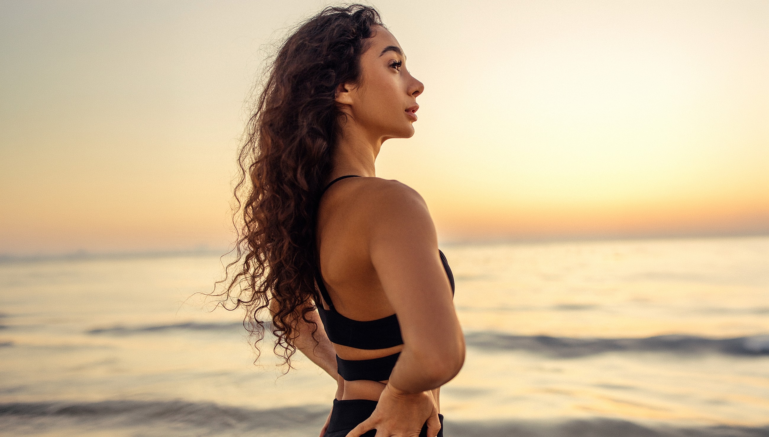 Woman gazing at ocean during sunset.