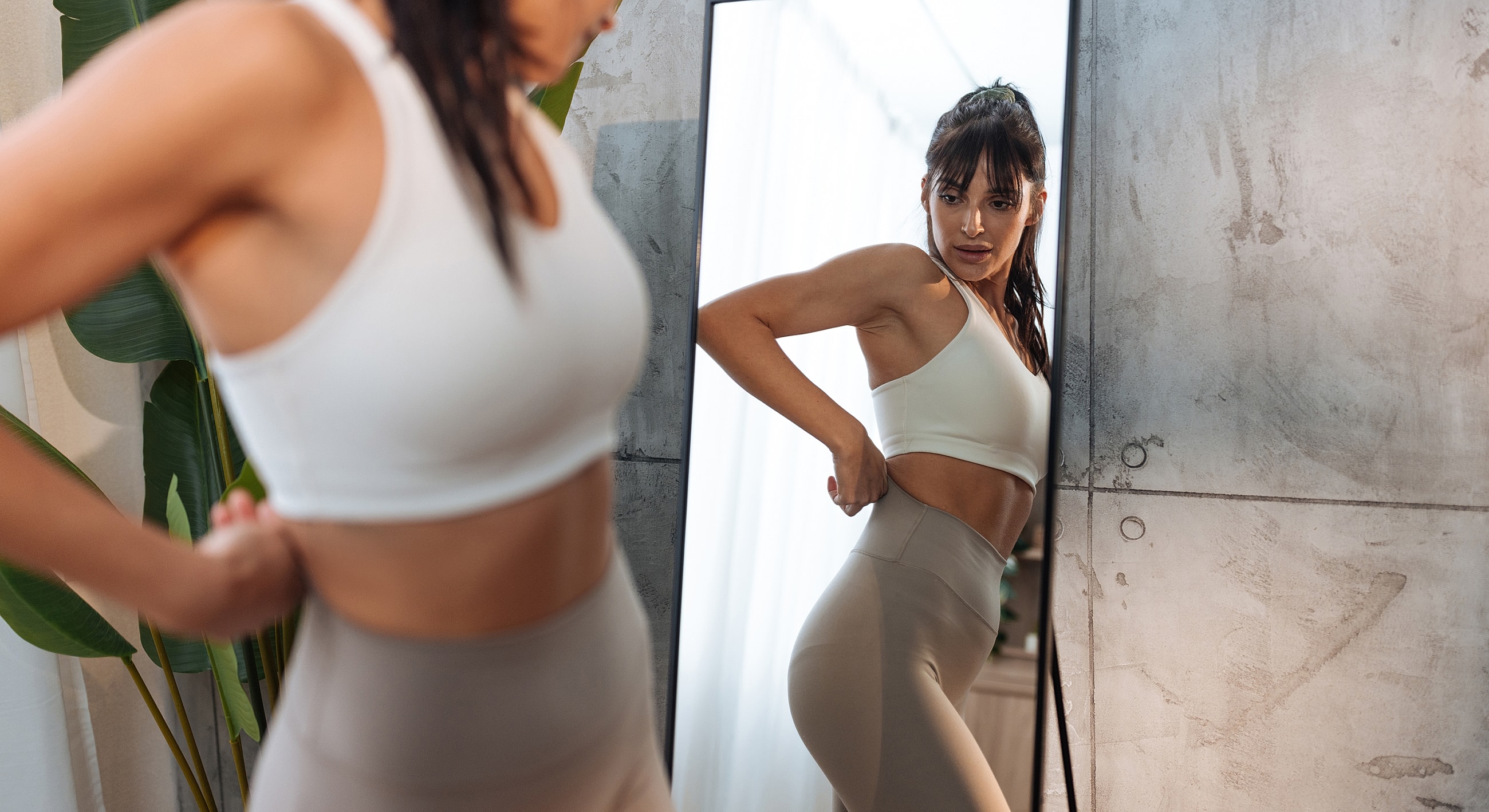 Woman adjusting athletic wear in front of mirror.