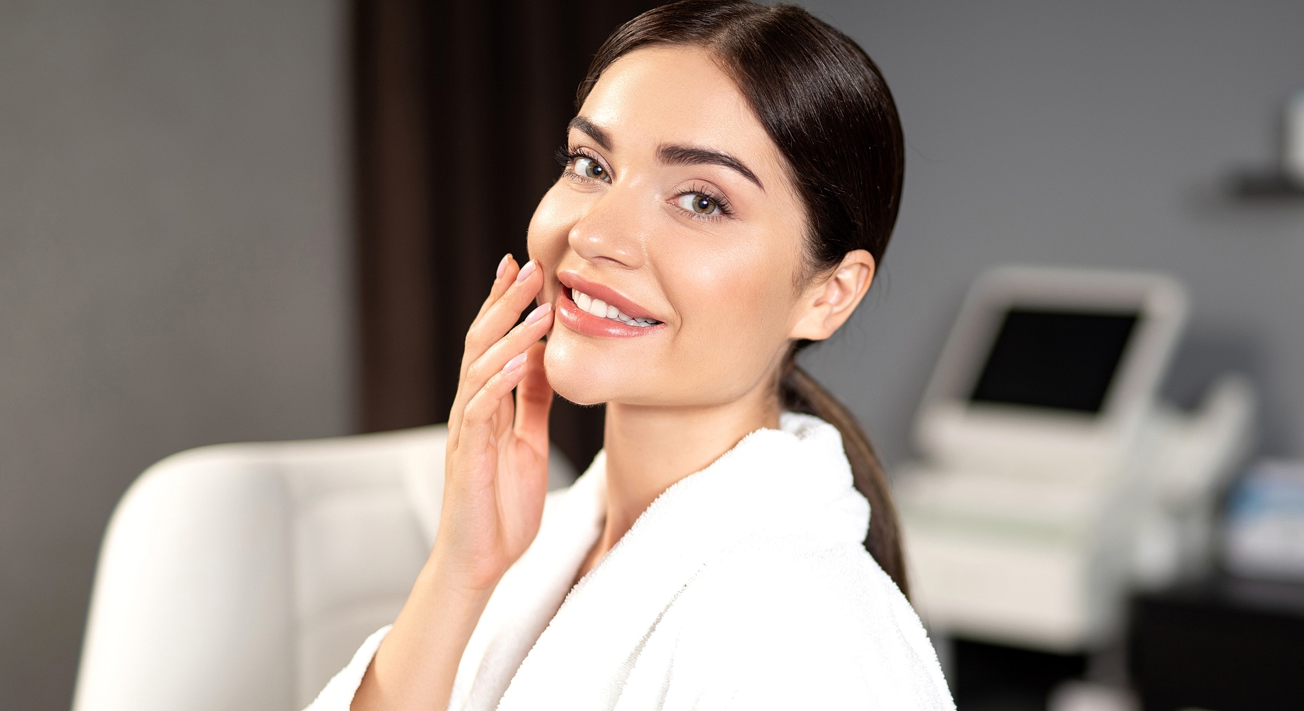 Smiling woman in a spa robe, skincare setting.