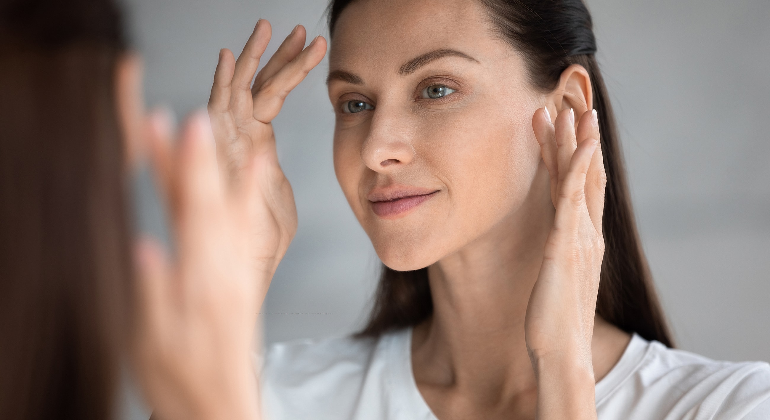 Woman applying skincare in front of mirror.