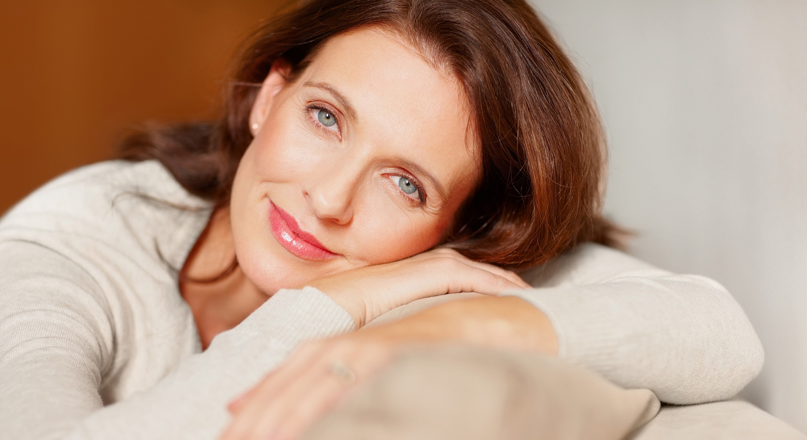 Woman resting her chin on hands, smiling gently.