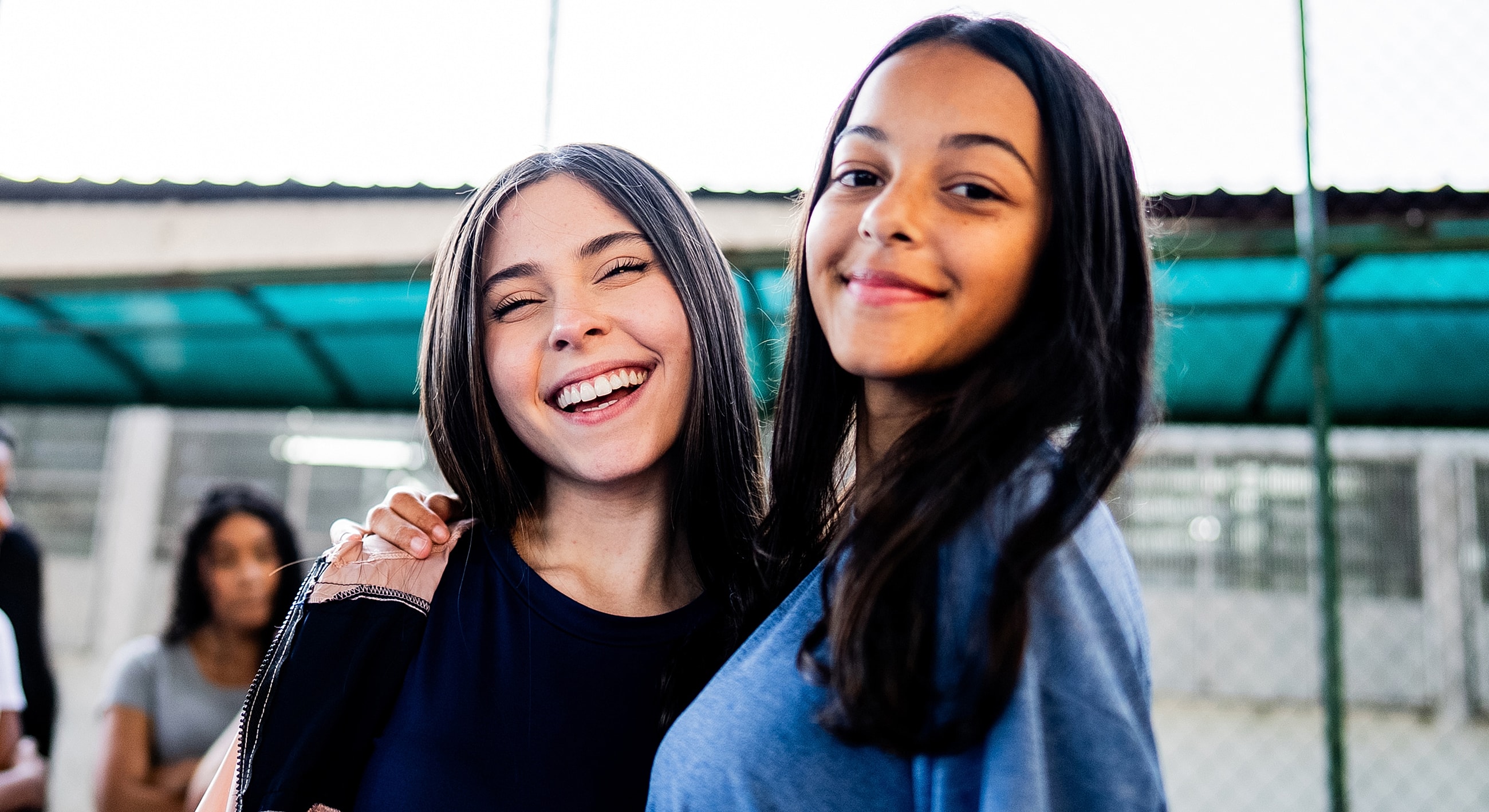 Two smiling friends at an outdoor gathering.